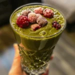 Refreshing green tea energy booster smoothie in a glass, with tea leaves and mint.